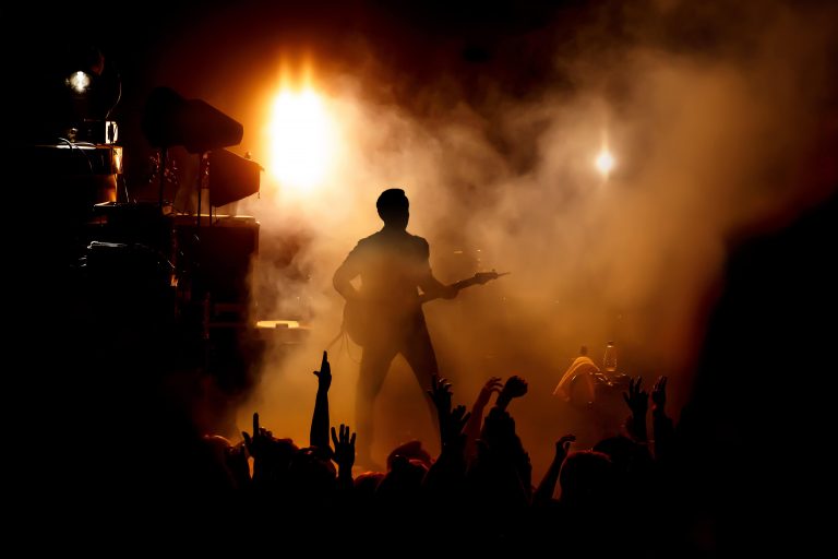 Silhouette of the guitarist on stage over the fans